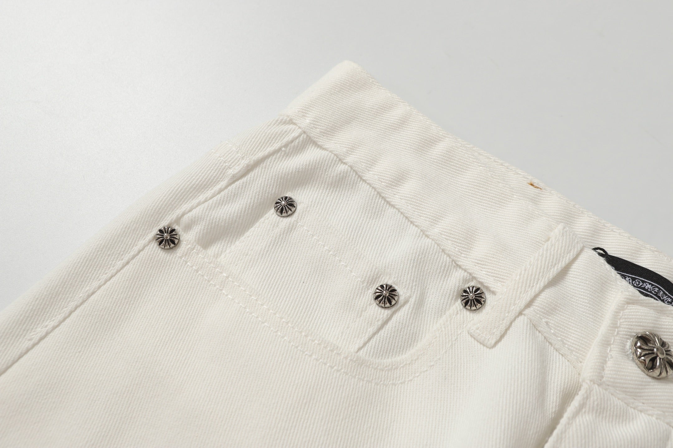 Chrome Hearts' classic white denim jeans with a colored leather cross wash.