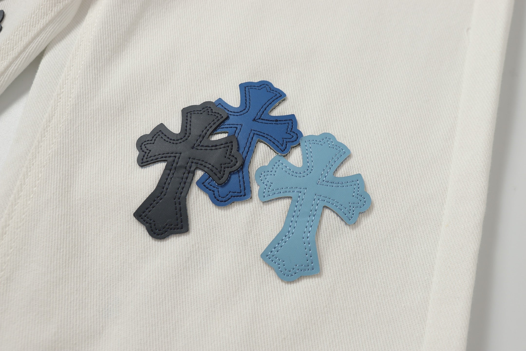 Chrome Hearts' classic white denim jeans with a colored leather cross wash.
