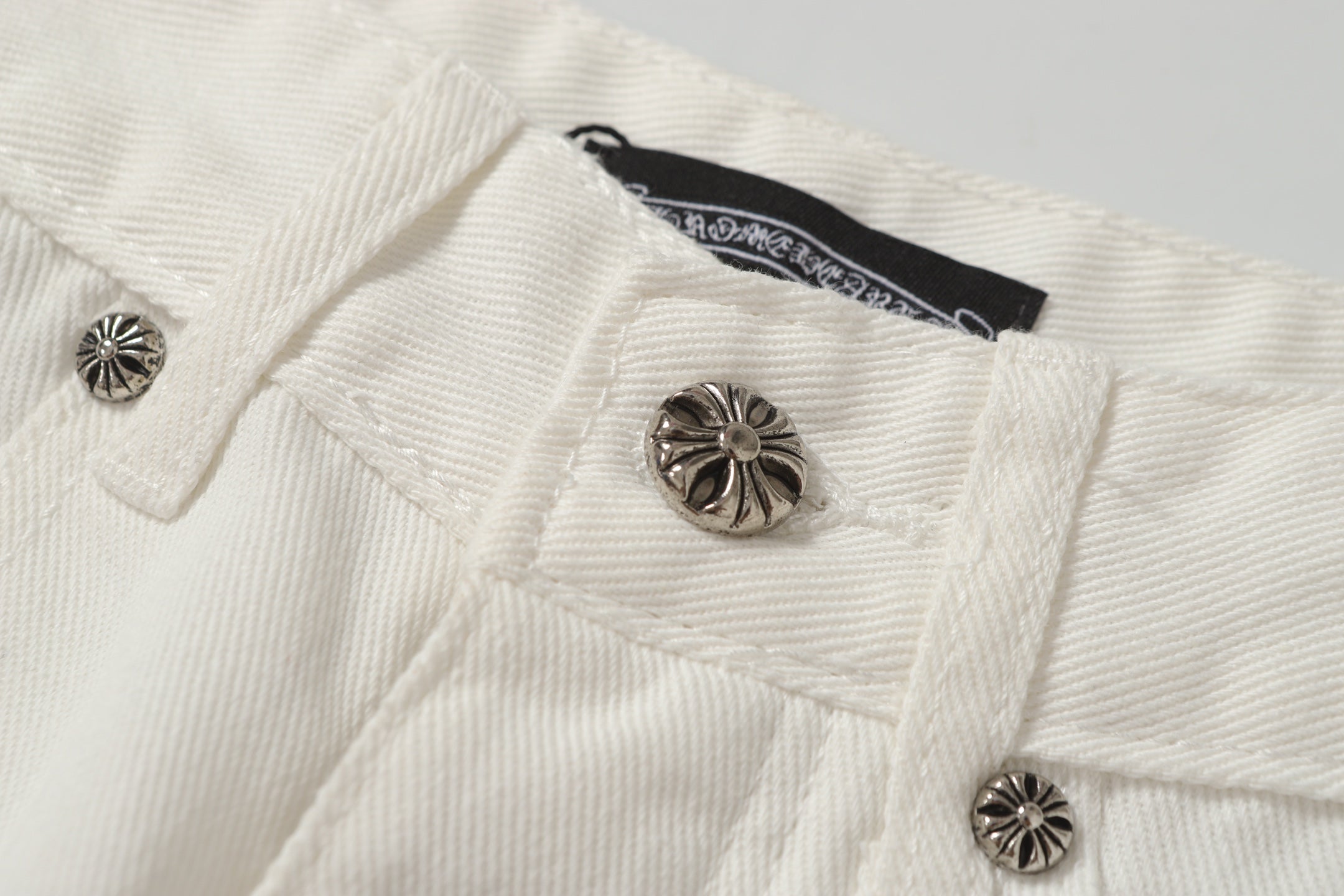 Chrome Hearts' classic white denim jeans with a colored leather cross wash.