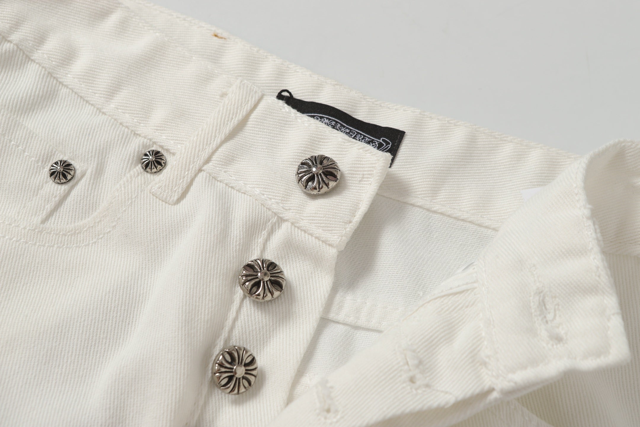 Chrome Hearts' classic white denim jeans with a colored leather cross wash.